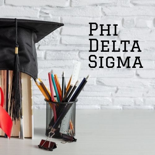graduation cap on some books next to a cup of pencils with words on wall "Phi Delta Sigma"